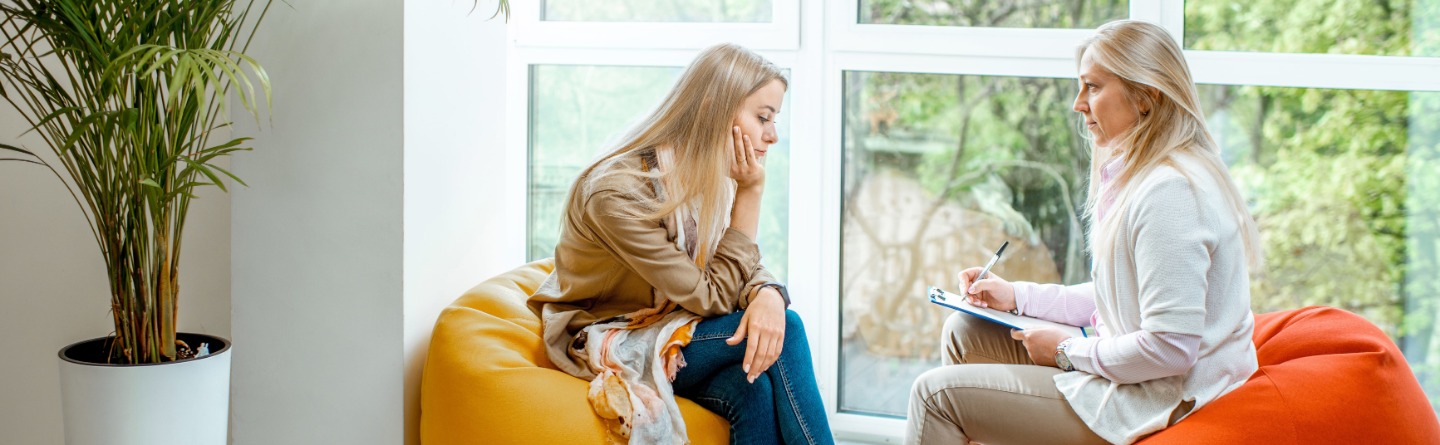 HIV Beratungsstelle Beraterin und junge Frau sitzen auf Sitzsäcken an einem Fenster