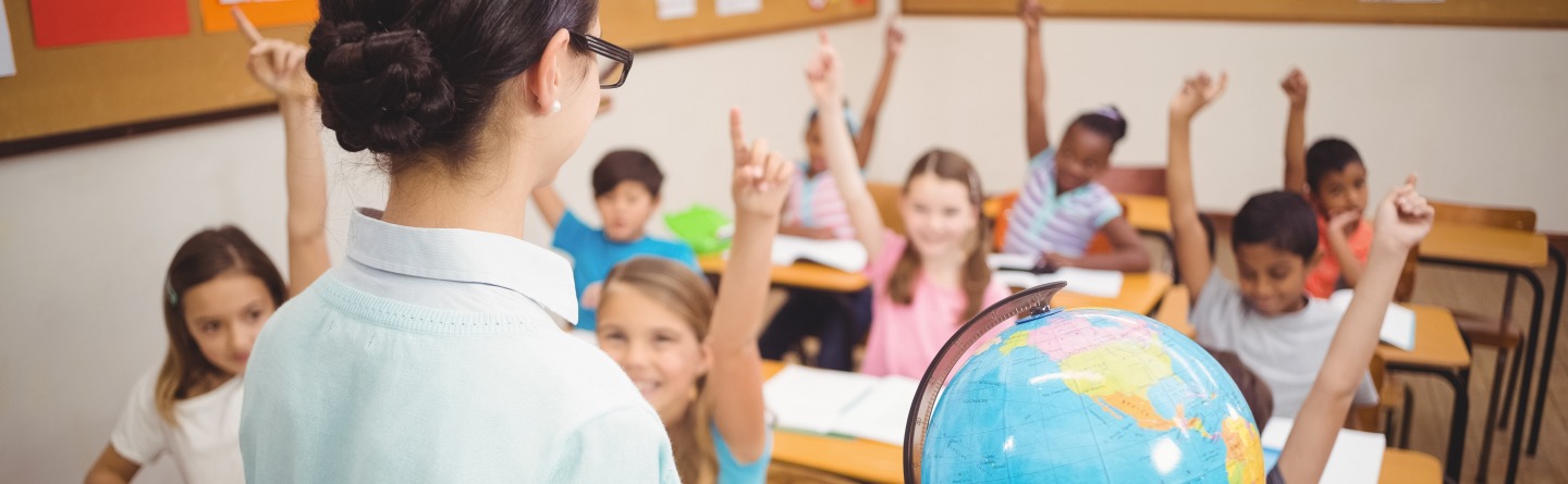 Header: Eine Lehrerin zeigt Schülerinnen und Schülern unterschiedlicher Herkunft etwas auf einem Globus. 