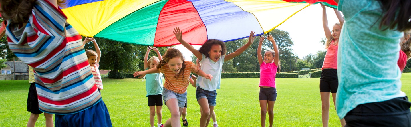 Header: Einige Kinder spielen gemeinsam und mit viel Freunde mit einem großen Schwungtuch.