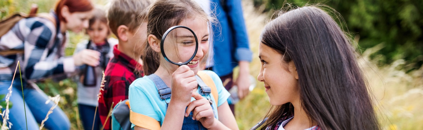Header: Einige Kinder sind gemeinsam mit ihren Betreuern in der Natur unterwegs. 