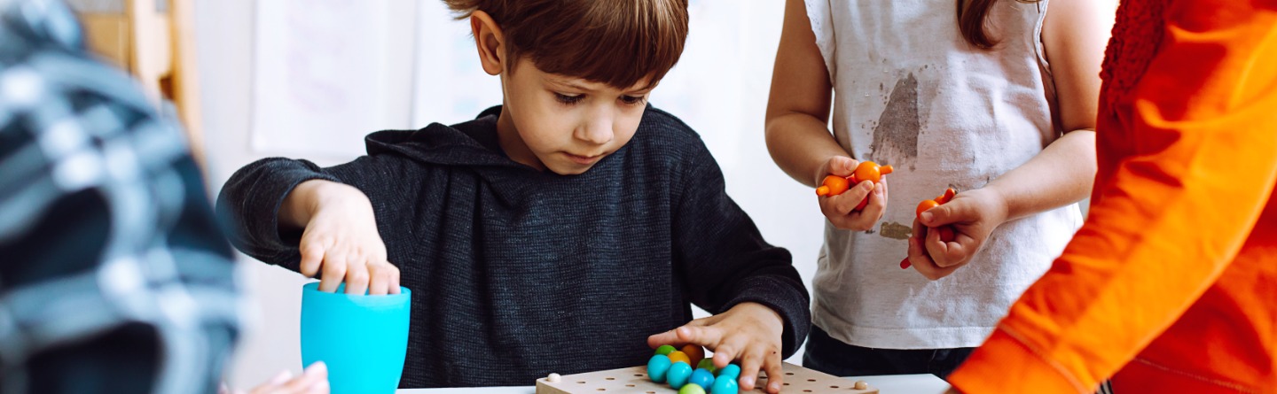 Header: Ein paar Kinder spielen im Kindergarten mit Holzkugeln 