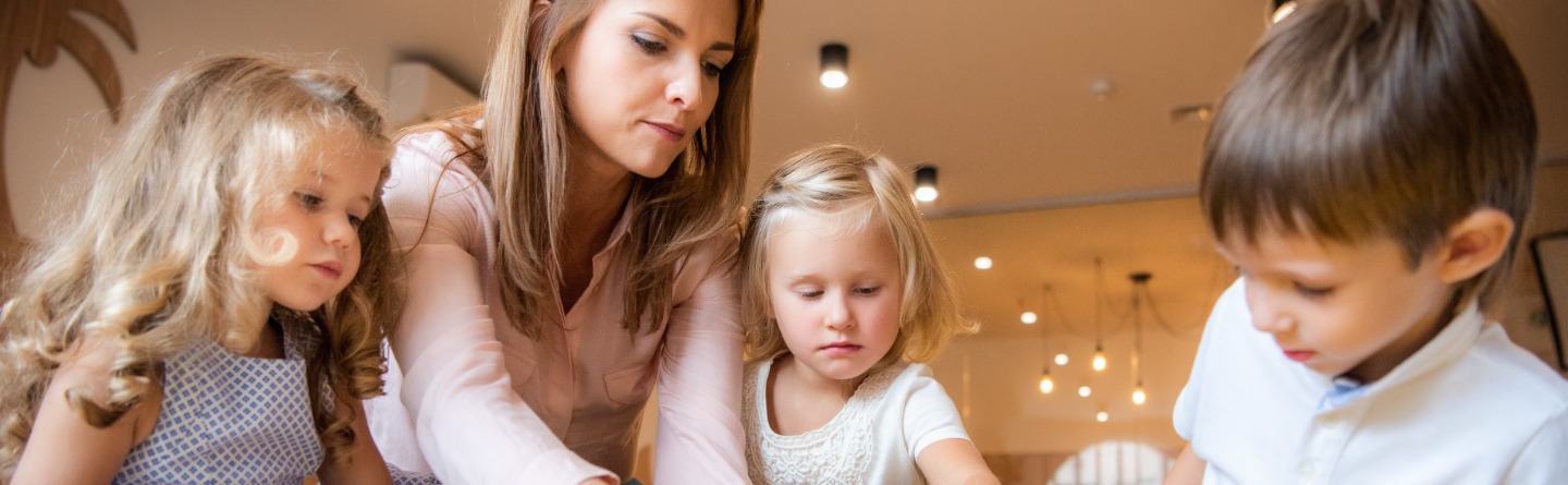 Header: Drei Kinder spielen gemeinsam mit ihrer Tagesmutter 