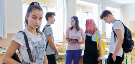 Kachel: Fünf Jugendliche befinden sich in einem Klassenzimmer und unterhalten sich miteinander. 