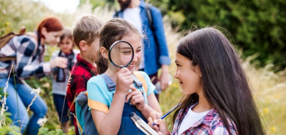 Kachel: Einige Kinder sind gemeinsam mit ihrem Betreuern in der Natur unterwegs. 