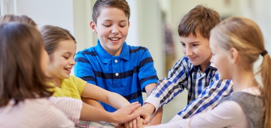 Header: Fünf Kinder legen ihre Hände zusammen und lachen 