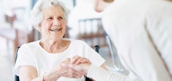 Kachel: Eine Seniorin schüttelt die Hand ihrer Pflegerin. Dabei lächelt sie glücklich. 