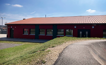 Endlich wieder ein Jugendtreff in Gunzenhausen News- Foto: Ein modernes, rotes Flachgebäude mit Fenstern, Zufahrt und Wiese bei klarem Himmel