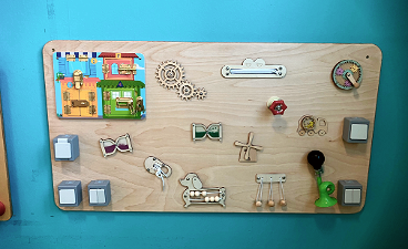 News- Foto: Ein Aktivitätsbrett aus Holz, welches an einer blauen Wand angebracht wurde