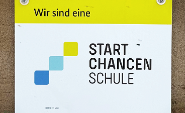 News- Foto: Farbiges Startchancen- Schild, welches am Schulgebäude angebracht ist