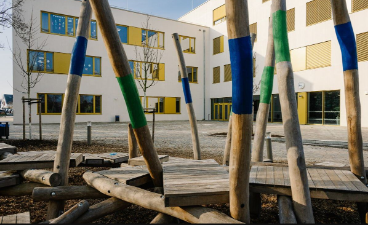 Das Schulgebäude von außen, im Vordergrund sind bemalte Baumstämme aufgebaut