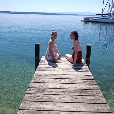 Zwei Frauen sitzen am Ende eines Badestegs am Starnberger See